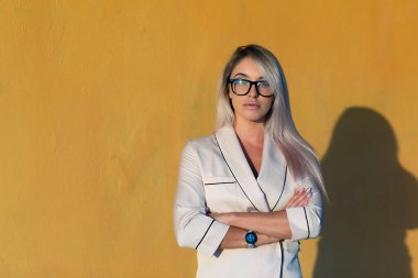 Güzel sarışın bir bej pantolon takım ve arka planı bardak portakal bir duvar