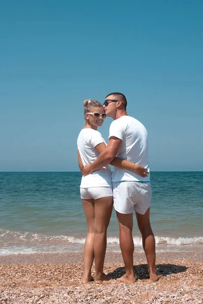 Back view of a romantic couple walking at beach during summer vacation. Lovers in white clothes.