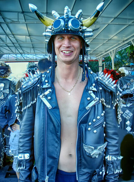 Brutal male biker in a leather jacket with spikes and a helmet with glasses and horns.