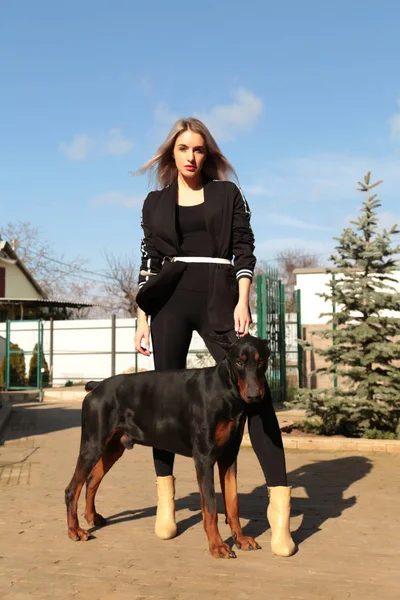 Beautiful young woman with her dog - doberman — Stock Photo, Image