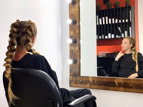 Парикмахер плетет волосы женщине в парикмахерской — стоковое фото