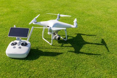 Beyaz profesyonel quadcopter dron kamera karşı arka planda yeşil çim yukarıdan uzaktan kumanda ile