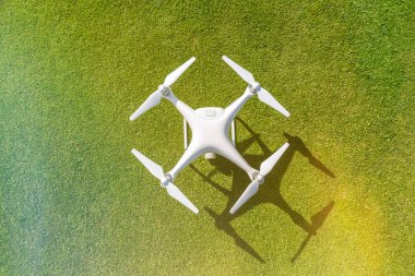 Beyaz profesyonel quadcopter dron kameraya üstten karşı arka planda yeşil çimen