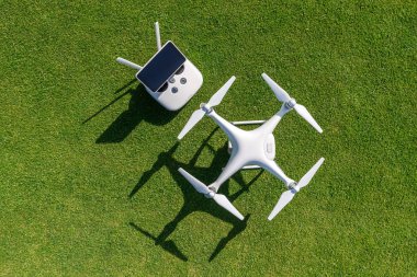 Beyaz profesyonel quadcopter dron kamera karşı arka planda yeşil çim yukarıdan uzaktan kumanda ile