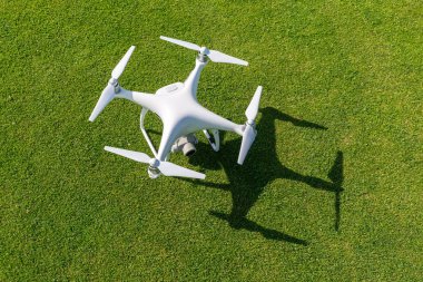 Beyaz profesyonel quadcopter dron kameraya üstten karşı arka planda yeşil çimen