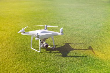 Beyaz profesyonel quadcopter dron kameraya üstten karşı arka planda yeşil çimen