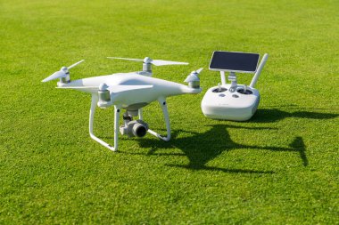 Beyaz profesyonel quadcopter dron kamera karşı arka planda yeşil çim yukarıdan uzaktan kumanda ile