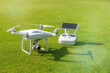Beyaz profesyonel quadcopter dron kamera karşı arka planda yeşil çim yukarıdan uzaktan kumanda ile