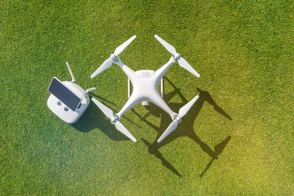 Beyaz profesyonel quadcopter dron kamera karşı arka planda yeşil çim yukarıdan uzaktan kumanda ile