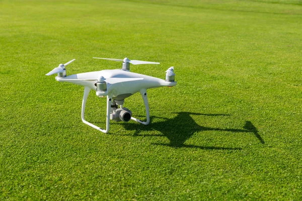 White professional quadcopter drone camera from above against green grass in background