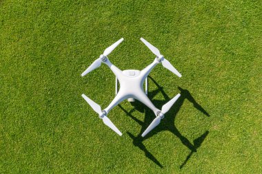 Beyaz profesyonel quadcopter dron kameraya üstten karşı arka planda yeşil çimen
