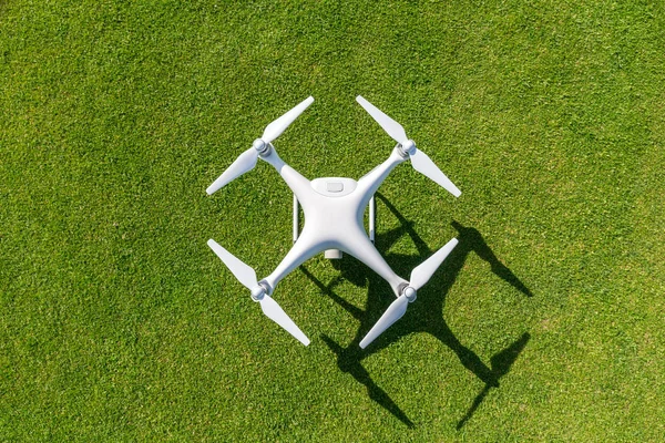 White professional quadcopter drone camera from above against green grass in background