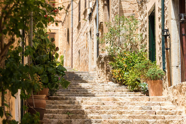 Mediterranean alleyway in Mallorca Spain with stairs in an ancient and narrow way with village houses and green plants