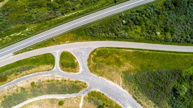 Yeşil çim ve ağaçların yukarıdan drone ile alınan çevrili eğri yol ve bisiklet lane 