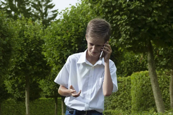 少年は 感情的に公園で電話で話す夏の日 — ストック写真