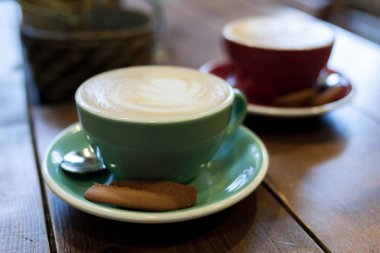 Kafedeki ahşap bir masada kapuçino bardağı.