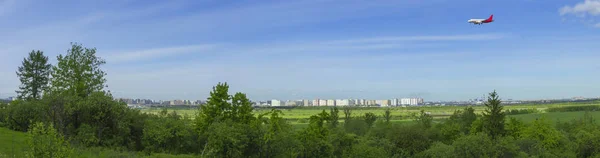 Městské panorama s letadlem v zemi za jasného dne — Stock fotografie