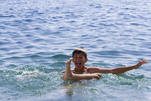 Der Teenager schwimmt bei klarem Tag im blauen Meer — Stockfoto