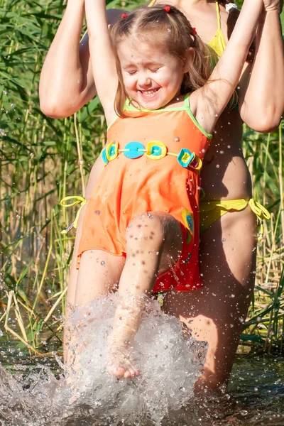 晴れた夏の日に湖で母と一緒に泳ぐ美しい3歳の少女 — ストック写真