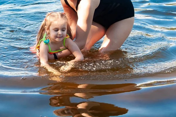 晴れた夏の日に湖で母と一緒に泳ぐ美しい3歳の少女 — ストック写真