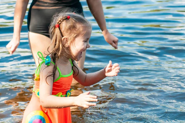 晴れた夏の日に湖で母と一緒に泳ぐ美しい3歳の少女 — ストック写真
