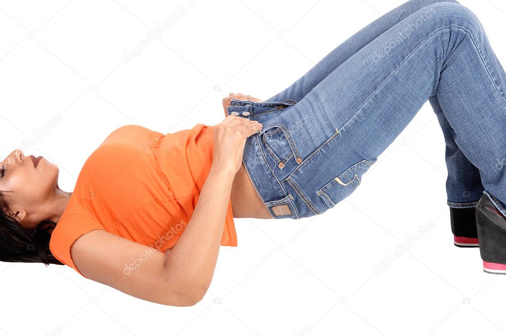 A slim young woman lying on her back on the floor try to put her jean