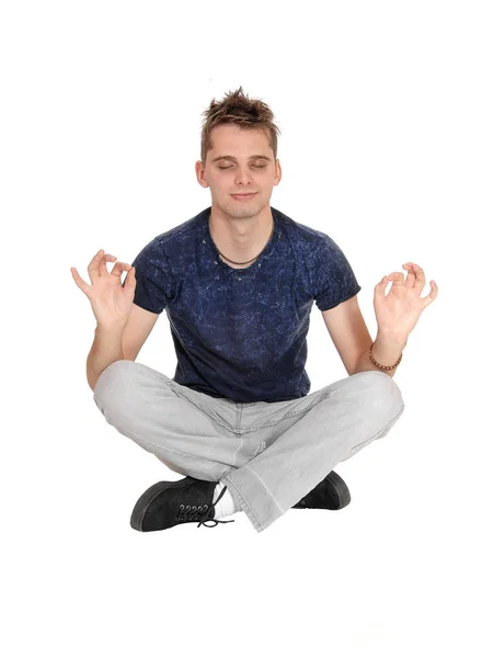 Молодой человек сидит на полу в позе йоги — стоковое фото
