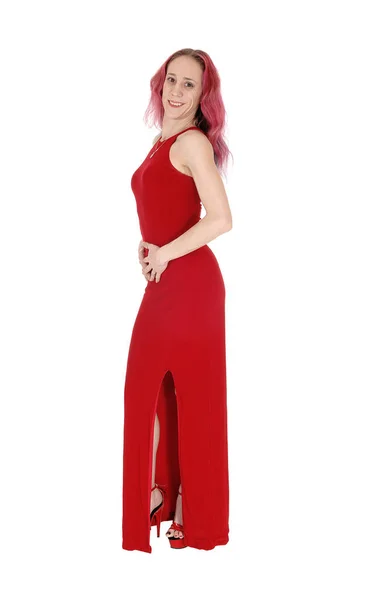 Young woman in a long red dress standing in profile — Stock Photo, Image