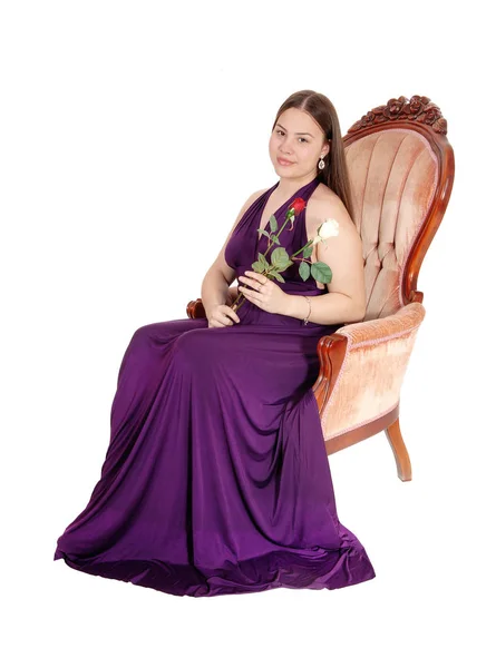 A smiling teenage girl sitting in an armchair in a long dress — Stock Photo, Image