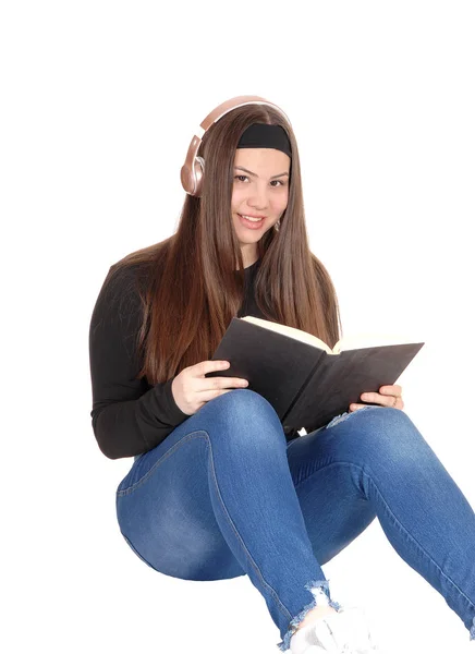 Preciosa joven adolescente sentada en el suelo con auriculares y readi —  Fotos de Stock