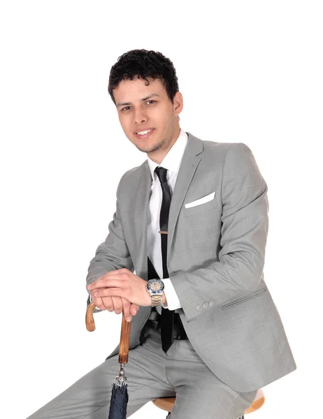 Young handsome man sitting with a umbrella and smiling — Stock Photo, Image