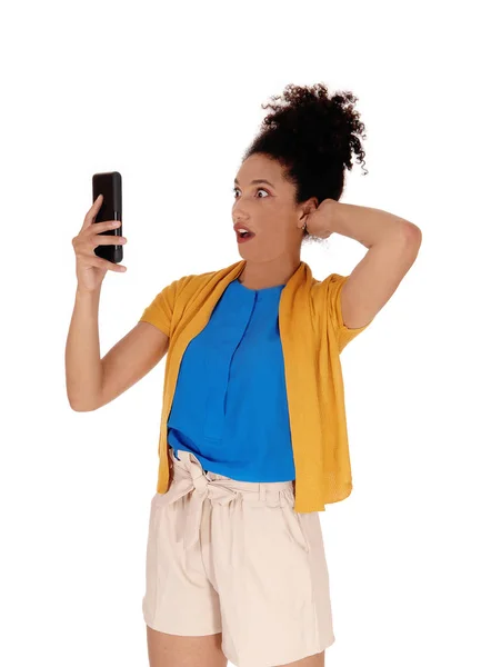 Потрясенная многорасовая женщина смотрит на свой мобильный телефон — стоковое фото