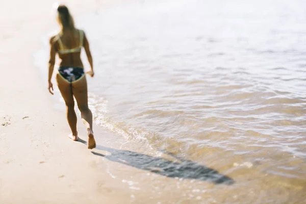 Mladá žena kráčející po pláži — Stock fotografie