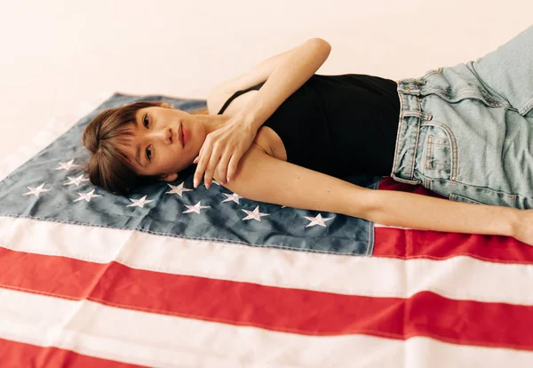 Mooie Aziatische vrouw op de Amerikaanse vlag Stockfoto