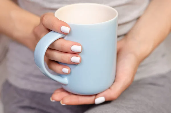 Mulher sentada com uma caneca de chá nas mãos — Fotografia de Stock