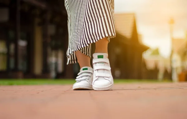 Female legs in street sneakers on blur background beauty fashion