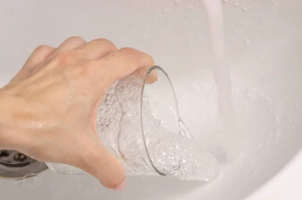 Eau à la main féminine dans un lavabo en verre — Photo