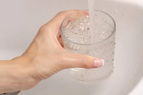 Eau à la main féminine dans un lavabo en verre — Photo