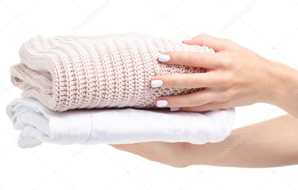 Stack of clothing white jeans and beige sweater in hand