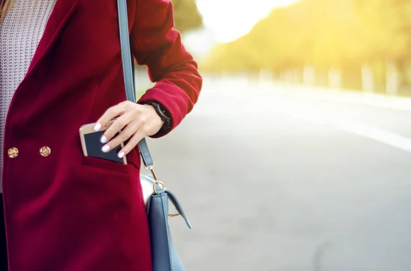Güzel kadın kadın çanta ceket kazak kot gülümseme izle smartphone cep telefonu — Stok fotoğraf