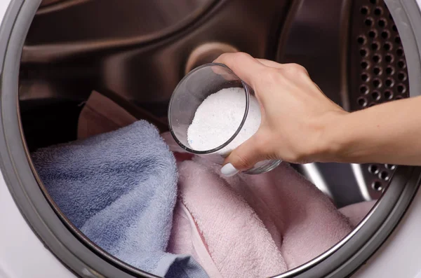 Perto de uma mão derramando detergente na máquina de lavar roupa — Fotografia de Stock
