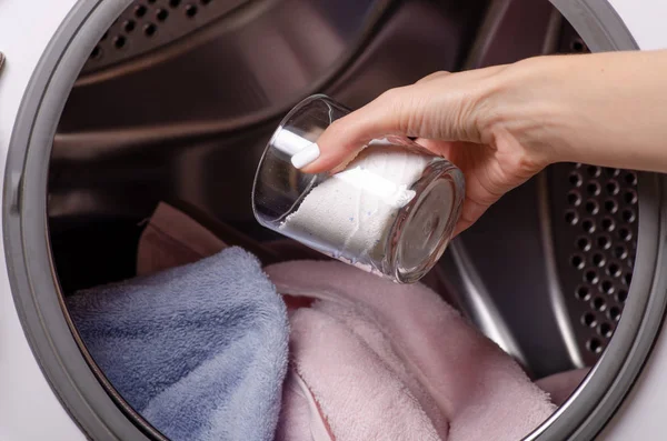 Perto de uma mão derramando detergente na máquina de lavar roupa — Fotografia de Stock