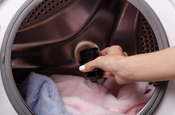 Mão segurando gel de lavagem no tambor da máquina de lavar roupa — Fotografia de Stock
