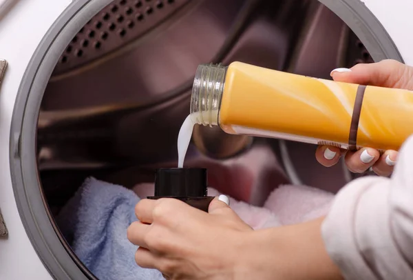 Mão segurando gel de lavagem no tambor da máquina de lavar roupa amaciador de tecido — Fotografia de Stock