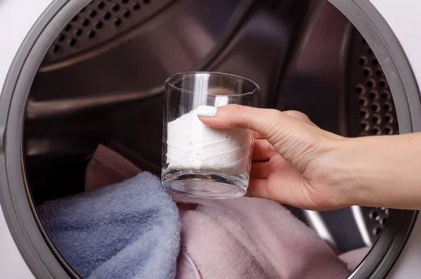 Perto de uma mão derramando detergente na máquina de lavar roupa — Fotografia de Stock