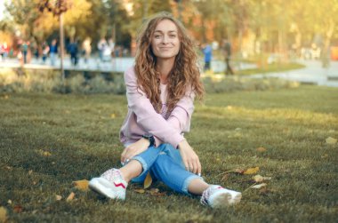 Kot pantolon ve bir kazak sokak spor ayakkabıları sonbahar park gülümseyen içinde mutlu güzel kadın