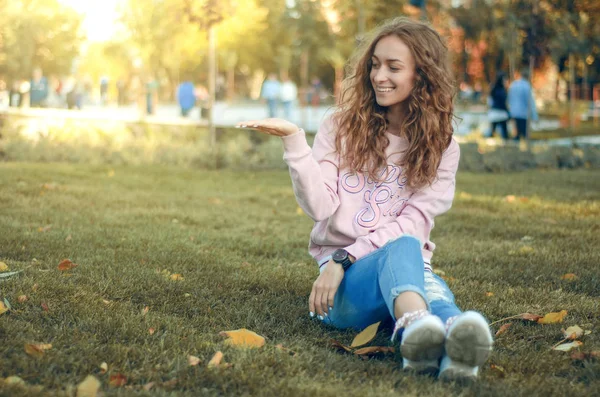 Mulher bonita em jeans e uma camisola no parque de outono tênis de rua mostrando mão — Fotografia de Stock