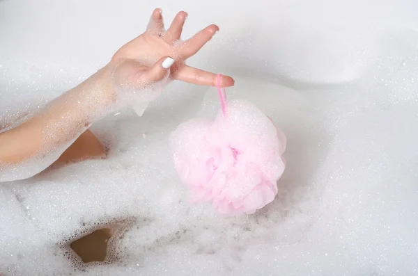 Beautiful woman in bath foam beauty health legs in gand shower sponge — Stockfoto