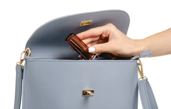 A hand put cosmetic lipstick lip gloss in the female blue gray leather handbag — Stock Photo, Image