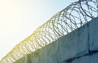 Beton bir çitin üzerindeki dikenli tel